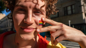 A close-up of an lgbtq person with a rainbow flag painted on their cheek, happily confident, symbolizing pride, resilience, and starting again in recovery.