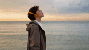 A young gay man standing peacefully by the ocean, showing healing from addiction and recovery.