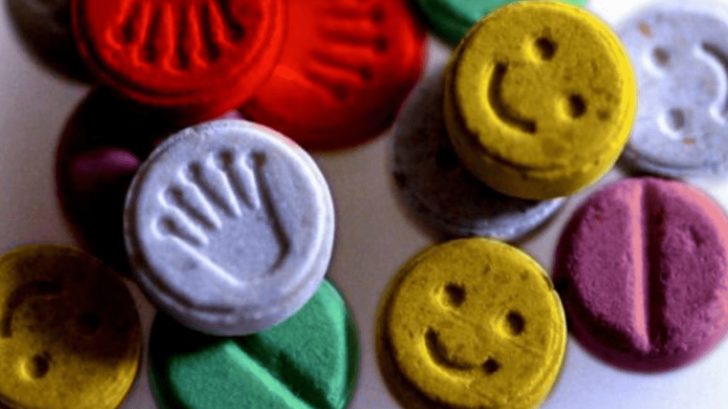 Colorful tablets with imprinted symbols and smiley faces, visually representing the party drug ecstasy, often used recreationally.