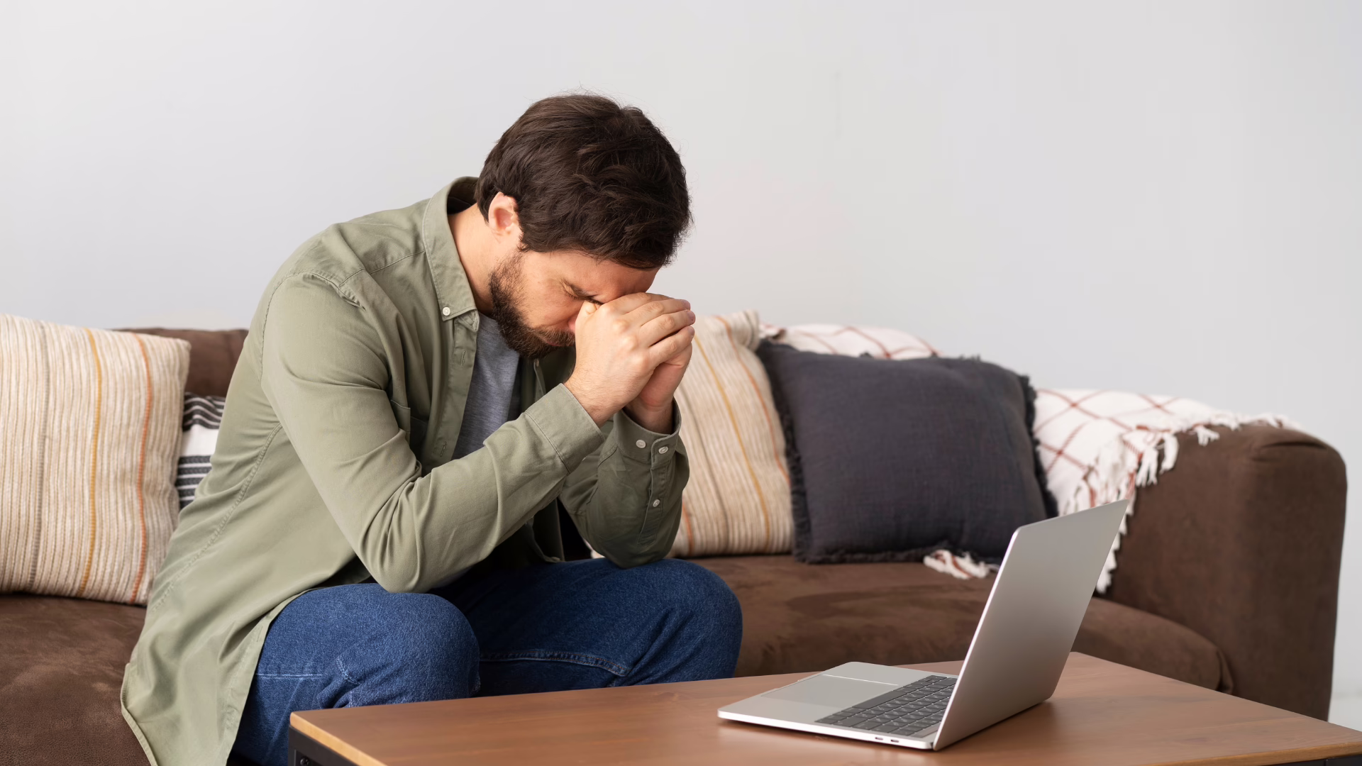 A gay person sitting on a couch trying to work without adderall.