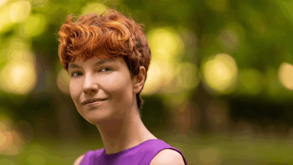 Person with short hair smiling peacefully outdoors, symbolizing self-acceptance and healing in gender identity and mental health